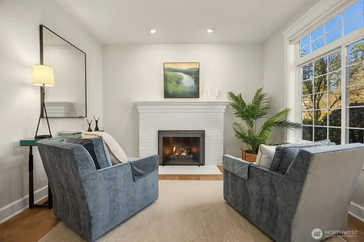 Painted brick, wood burning firepace with art wall and tall windows, a serene reading room.