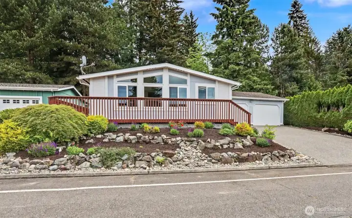 Street view with landscaped front yard and the large front wrap around deck.