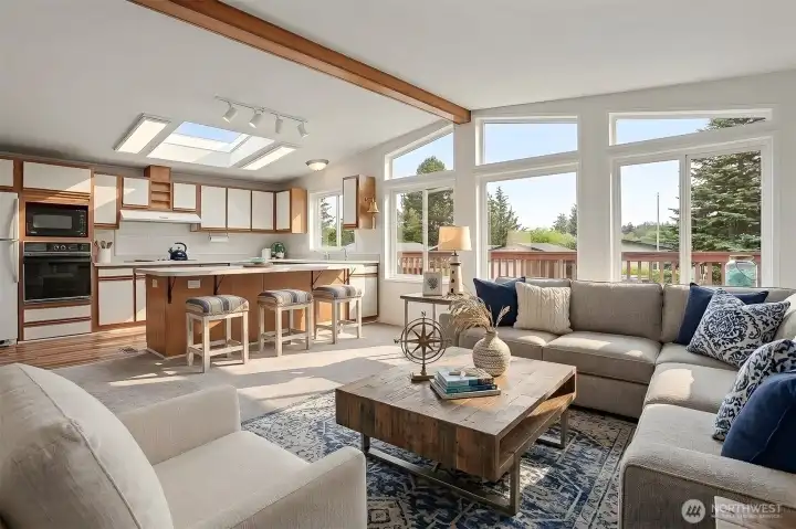 Family room features vaulted ceilings, wall of double pane updated windows with light and bright western exposure and new wall to wall carpet.  Opens to kitchen with an eating bar and skylight.  Virtually staged photo.