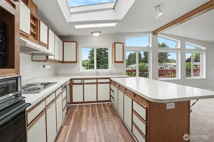 Spacious gourmet kitchen features new LVP flooring, skylights, wall oven, cooktop, western exposure and eating bar opening to the family room.