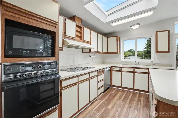 Spacious gourmet kitchen features new LVP flooring, skylights, wall oven, cooktop, western exposure and eating bar opening to the family room.