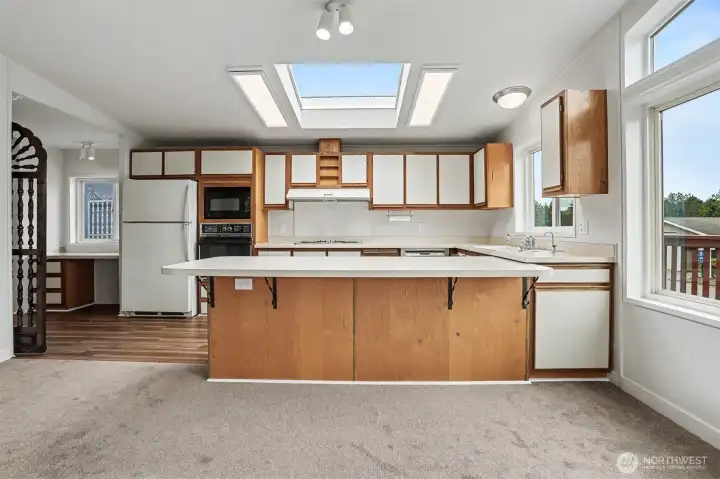 Spacious gourmet kitchen features new LVP flooring, skylights, wall oven, cooktop, western exposure and eating bar opening to the family room.