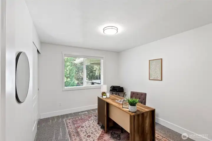 Bedroom 2, located on the main level, currently staged as a home office with new plush carpet.