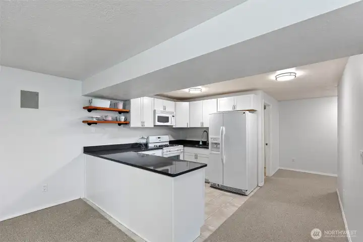 Lower level L-shaped kitchen and hall to bathroom and stairs.
