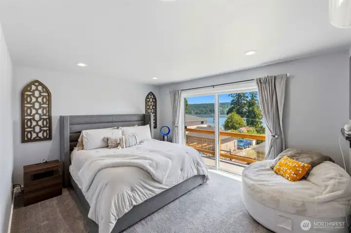 Primary bedroom with slider to upper balcony with water and Mt. Rainier views Primary bedroom with slider to upper balcony with water and Mt. Rainier views
