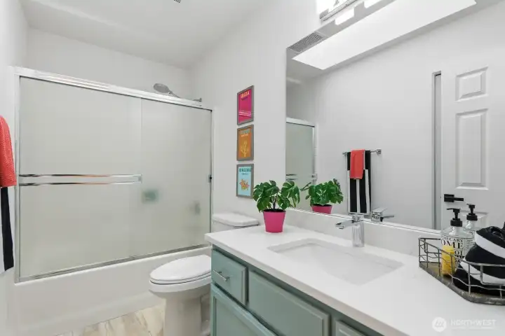 Remodeled full guest bathroom featuring new LVP floors, quartz counters, undermount sink, faucets, hardware, and lighting.