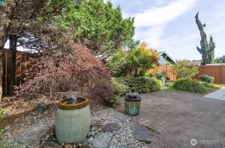 This private fenced back yard has extended paved patio area, mature landscaping.  The bubble fountain offers soothing sounds and invites native birds to stop and take a drink.