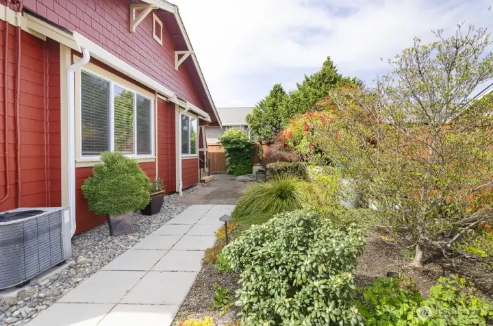 View of the back of the home with paved walk way.  Lovely mature plantings, all on drip system.