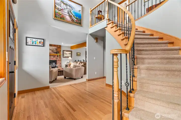 Grand inviting entry with beautifully refinished oak flooring, custom curved 2 stairway as heart of home