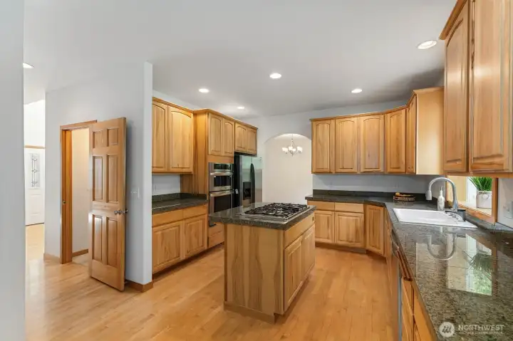 Custom cabinetry, granite countertops, a 5-burner propane cooktop with downdraft venting on the island, and a large walk in pantry make this kitchen built for real use. Custom cabinetry, granite countertops, a 5-burner propane cooktop with downdraft venting on the island, and a large walk in pantry make this kitchen built for real use.