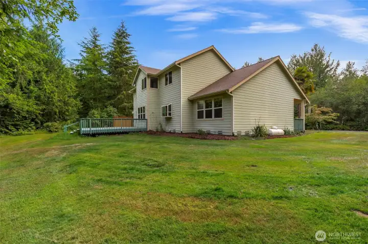 A generous lawn wraps around the back of the home, with the deck accessible from the great room and mature trees framing the property on all sides. A generous lawn wraps around the back of the home, with the deck accessible from the great room and mature trees framing the property on all sides.
