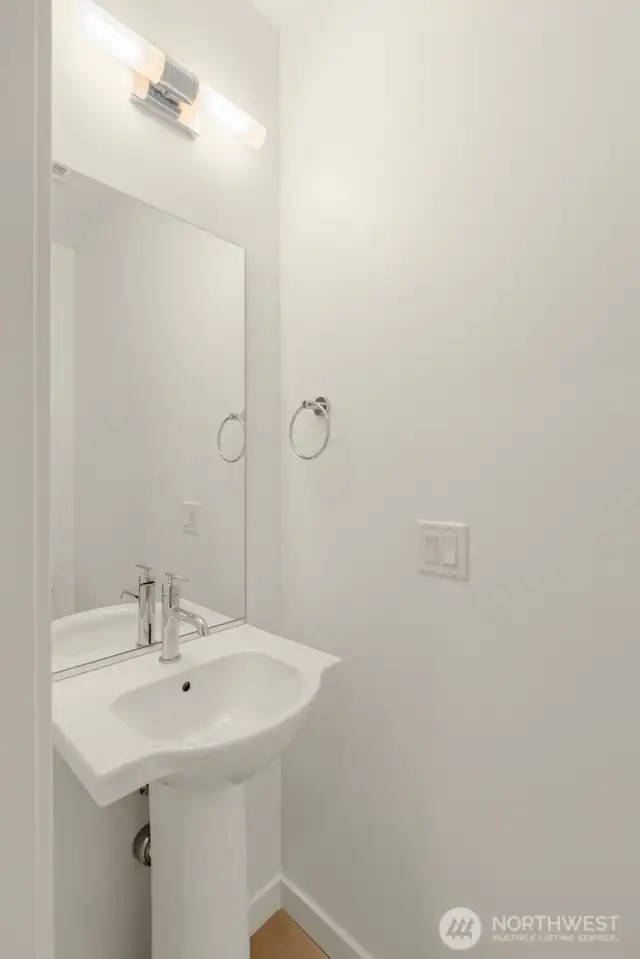 A chic powder room that gets the job done—stylish lighting, a modern pedestal sink, and perfect for guests popping by.