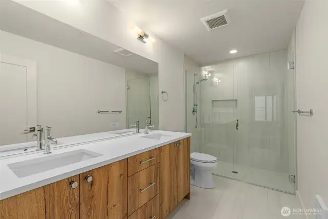 Your spa moment awaits. This luxe bath has a dual-sink vanity, wood tones for warmth, and a glass-enclosed shower you won’t want to leave.