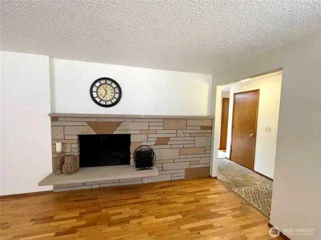 Living room with wood burning fireplace and original hardwood floors.