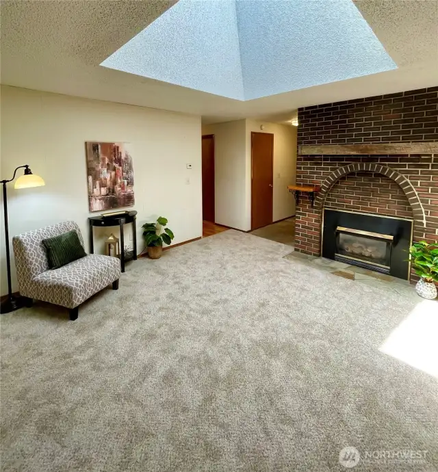 Family room with huge skylight boasts new carpet and a gas fireplace.