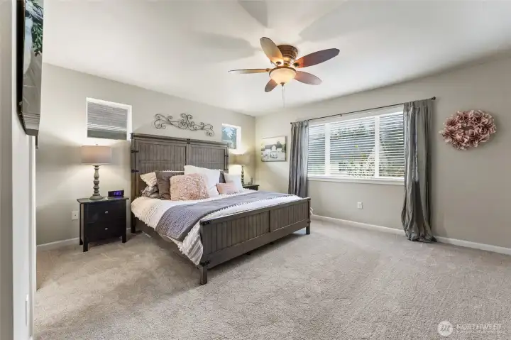 Primary bedroom at the top of the stairs is a spacious and generous room with several windows, and ceiling fan for comfort.