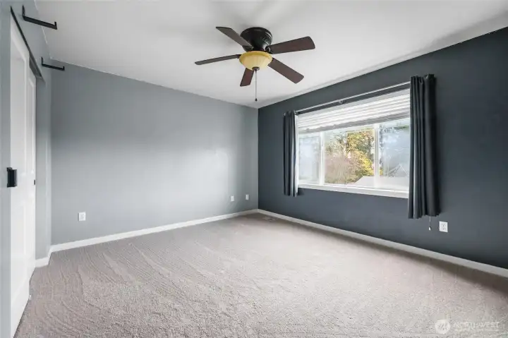 Bedroom #4 (large enough to be a bonus/flex room) in front of home, with large window and ceiling fan.