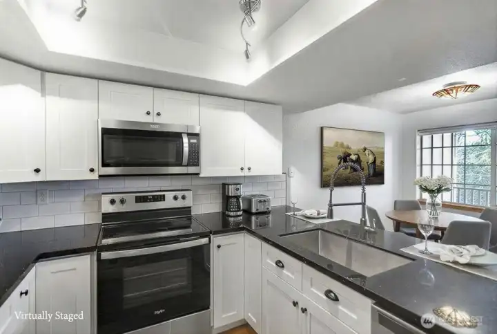 This bright, completely remodeled kitchen boasts a fresh, modern design with the inclusion of brand new, stylish cabinets, providing an abundance of organized storage solutions. The space features high-end finishes throughout, highlighted by elegant quartz countertops, complemented by deep, durable stainless steel sinks, and the kitchen is further enhanced by the inclusion of newer, energy-efficient stainless steel appliances, creating a truly inviting and functional culinary area.