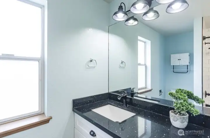 Here is a description for the bathroom photo: This is a well-maintained full bathroom featuring a recently updated vanity. The vanity boasts sleek quartz countertops, a brand new, stylish sink, and a gleaming, modern faucet, all contributing to a refreshed and contemporary feel.