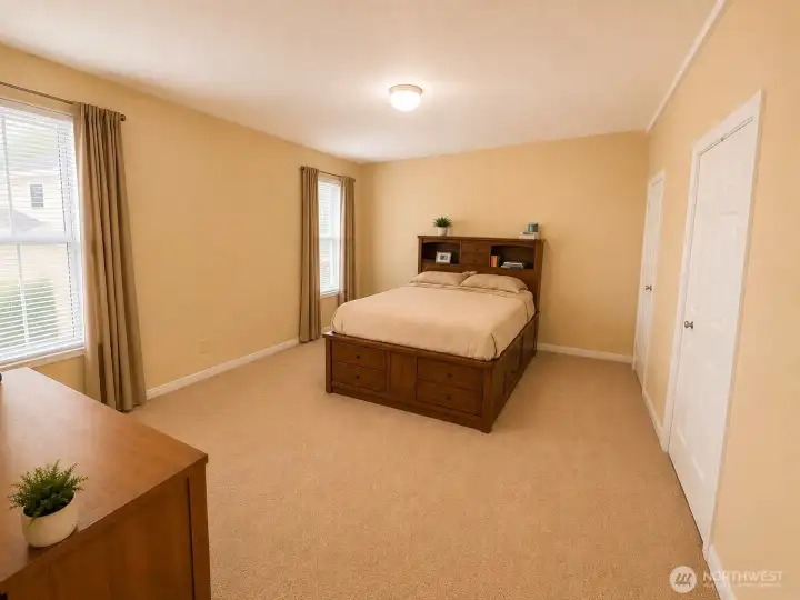 Spacious primary bedroom offers a peaceful retreat with generous proportions, soft natural light from multiple windows, and ample space for a king-size bedroom set. The thoughtful layout provides flexibility for additional seating or a workspace, while the neutral finishes create a warm and inviting atmosphere. Conveniently located within the home's functional floor plan, this comfortable suite offers the perfect place to relax and unwind at the end of the day.