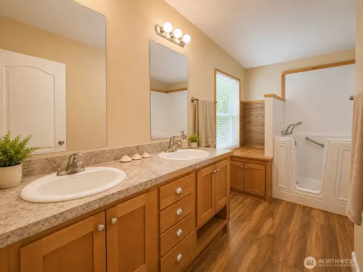 Large primary bath designed for both comfort and convenience, featuring dual vanities, generous storage, and a walk-in soaking tub with accessibility features. Bright and inviting, this well-appointed space provides the perfect combination of functionality and relaxation.