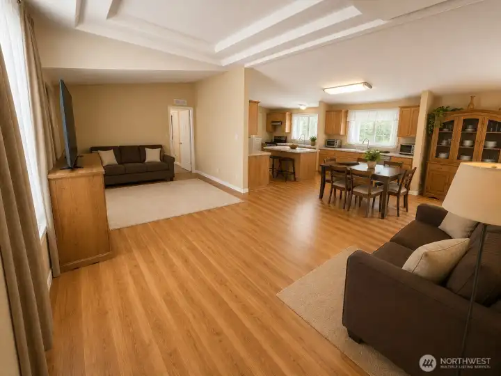 Spacious open-concept great room seamlessly connects the living area, dining space, and kitchen, creating an inviting layout ideal for everyday living and entertaining. Features include attractive laminate flooring, abundant natural light, a functional kitchen with center island, and generous gathering spaces that make the heart of the home feel warm, comfortable, and welcoming.