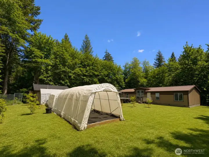 Wide-open lawn and multiple outbuildings create a versatile outdoor environment with endless possibilities. The property features a large storage shed, covered equipment shelter, and generous grassy areas surrounded by mature trees for privacy and seclusion. Ideal for gardening, hobbies, recreational equipment, animals, or additional storage needs, this usable outdoor space showcases the property's rural charm and functional flexibility. A peaceful setting with room to work, play, and enjoy the outdoors.