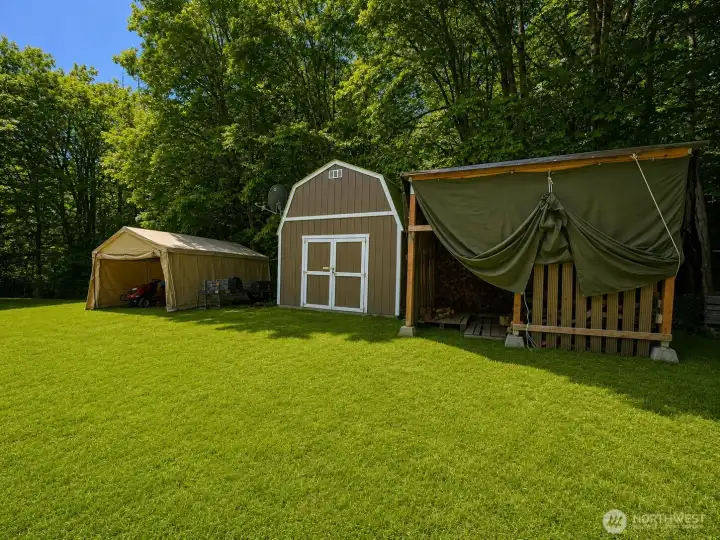 A collection of versatile outbuildings provides exceptional storage, workshop, and equipment space for a variety of uses. The property features a large barn-style storage building, covered shelter, and additional utility structures, all situated on a spacious, well-maintained lawn surrounded by mature trees. Whether you need room for tools, recreational vehicles, lawn equipment, hobbies, or future projects, these improvements offer outstanding flexibility and functionality in a private country setting. Perfect for those seeking extra workspace and abundant storage beyond the home itself.