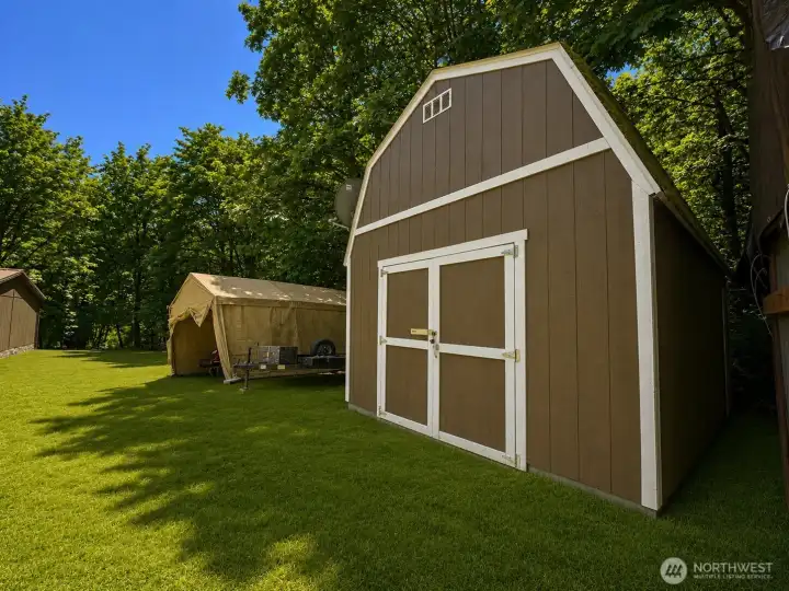 Large barn-style storage shed with wide double doors provides excellent space for tools, equipment, lawn machinery, recreational gear, or workshop use. Situated in a private, park-like setting surrounded by mature trees, the property also includes additional covered storage for trailers, vehicles, or outdoor equipment. Level grassy areas offer easy access and plenty of room for projects, gardening, or future improvements. A functional and versatile outdoor space with the storage capacity and flexibility that rural property owners appreciate.