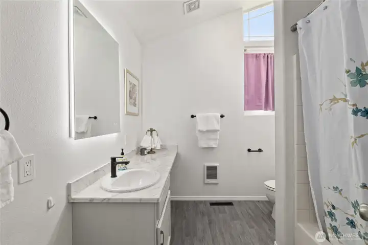 Full bathroom next to 2 of the bedrooms w/ large lighted mirror.