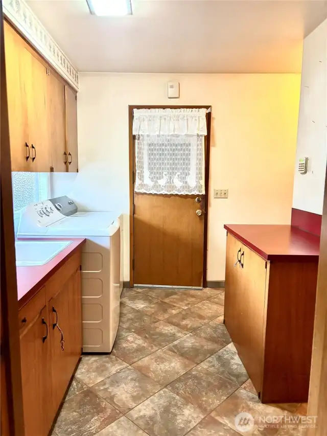 Large laundry room with 1/2 bath around corner and storage/pantry around nearest corner
