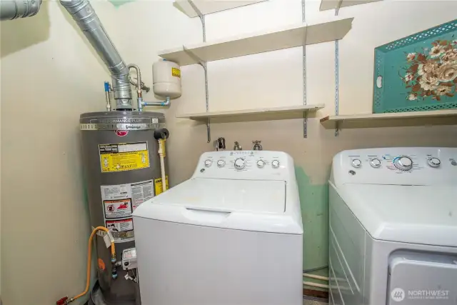 Laundry room off kitchen with furnace, hot water tank, washer, dryer and storage.