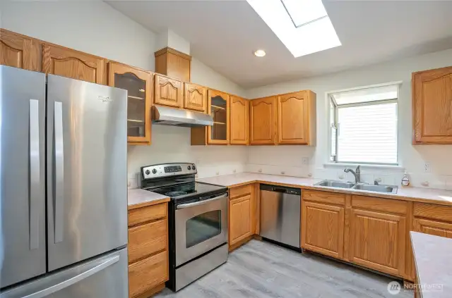 Kitchen features stainless steel appliances and a bay window framing the fenced backyard.