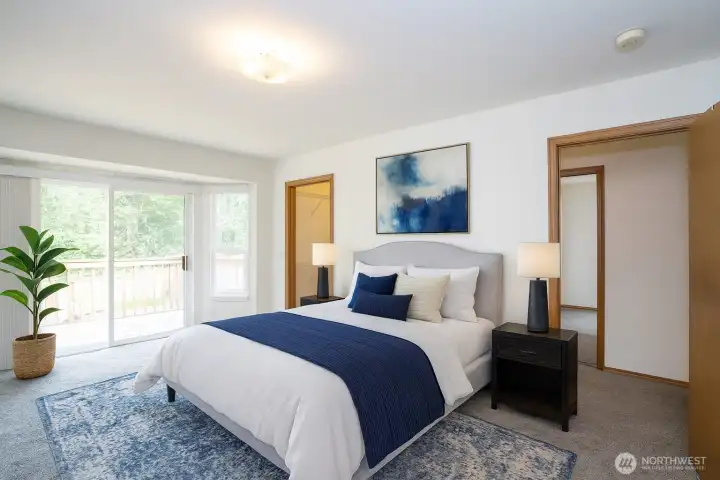 Main-level primary suite includes walk-in closet and direct access to 3-tier deck - Virtual Staged