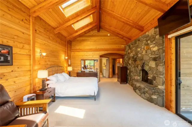 primary bedroom with skylights, fireplace, doors to the deck