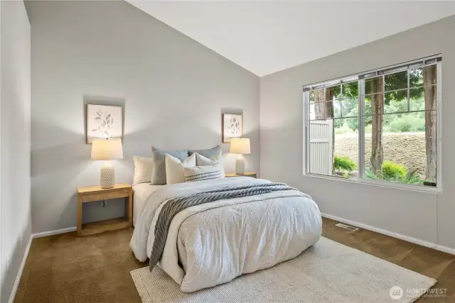 Primary bedroom filled with natural light and soaring vaulted ceilings.