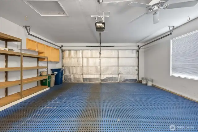 large Spacious 2-car garage featuring a ceiling fan and smart storage solutions.