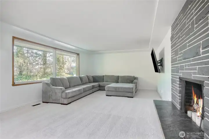 Open large living room with ambient lighting and beautiful fireplace with stone hearth.