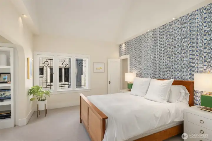 The upper-level primary bedroom is adorned with custom wallpaper, adding a touch of refined sophistication.