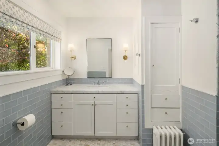 Retreat to the spa-like primary bathroom, featuring exquisite tile details and elegant Roman shades.