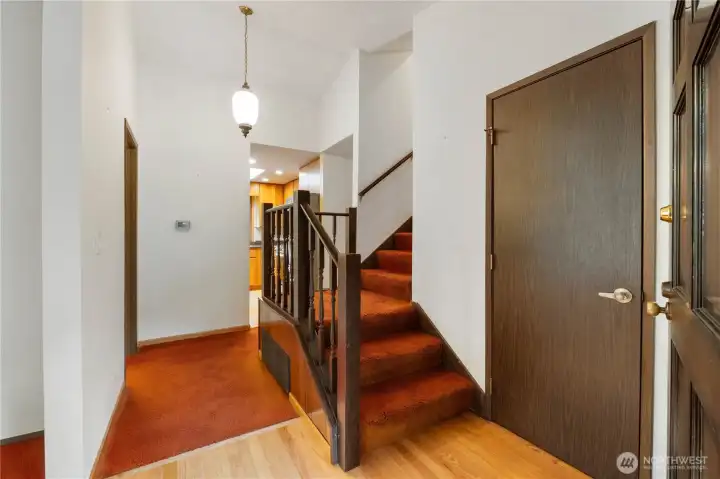 View of entry with coat-closet. Living room directly to the left, kitchen straight ahead, stairs to 2nd floor and around to the right leads to stairs to lower level.