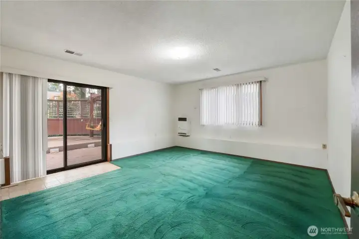 Unstaged Family Room on lower level with slider out to deck and backyard