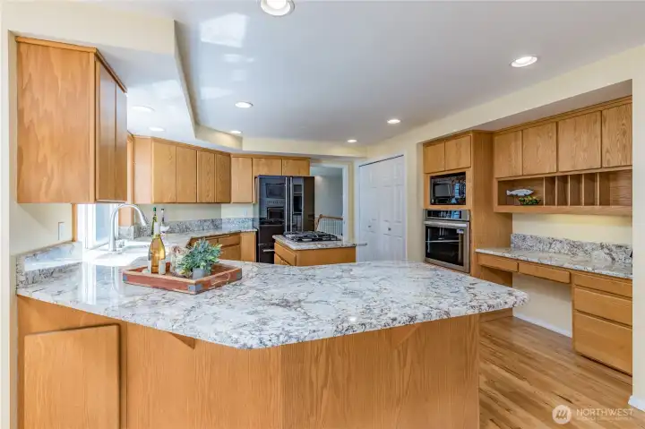 Gourmet kitchen with sleek granite counters, extensive cabinetry, and warm hardwood floors