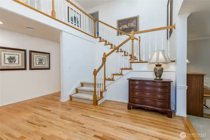 The open-concept design is highlighted by the elegant wood railing and balcony overlook, creating a seamless connection between the main level and the upstairs living quarters.