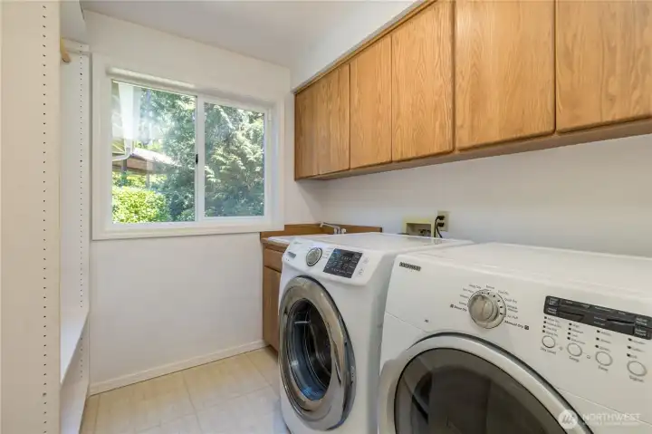 Main-floor laundry room with utility sink and generous cabinet storage, conveniently situated just off the garage entrance