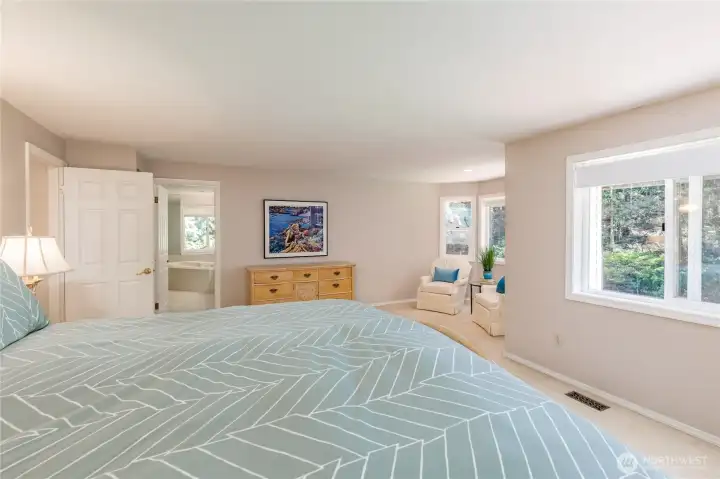 Another view of the primary suite highlighting the bright, open entry to the en-suite bath and the beautiful natural light that fills the entire space.