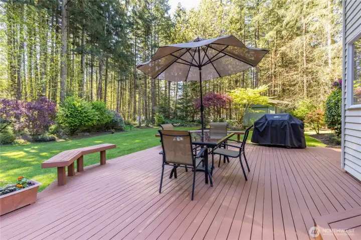 Host unforgettable summer gatherings on the expansive deck, featuring a dedicated space for outdoor dining and grilling, all set against a tranquil, evergreen backdrop.