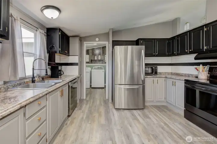 Remodeled Kitchen is ready for the cook! New floor, refinished cabinets, new appliances, fixtures, lighting and more... the doorway leads to the Utility Room and Garage!