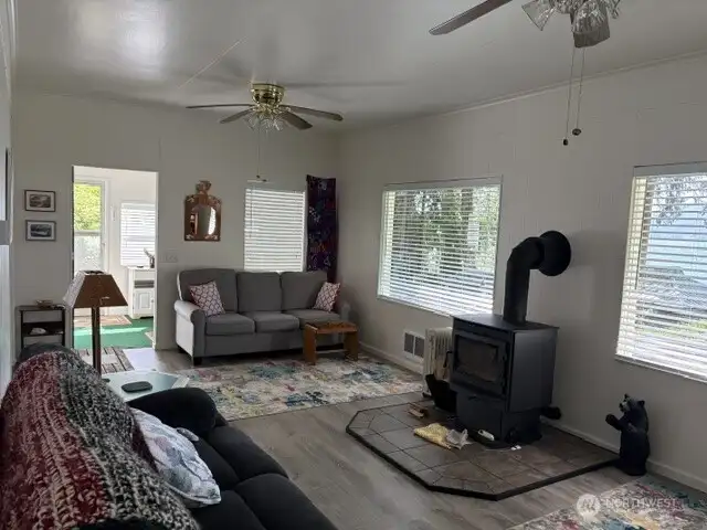 Sun room entrance to main living room. Newer plank flooring and picture windows providing abundant natural light.