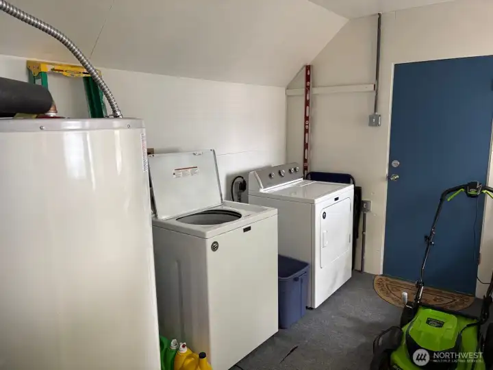 Utility room off of kitchen with newer washer and dryer.